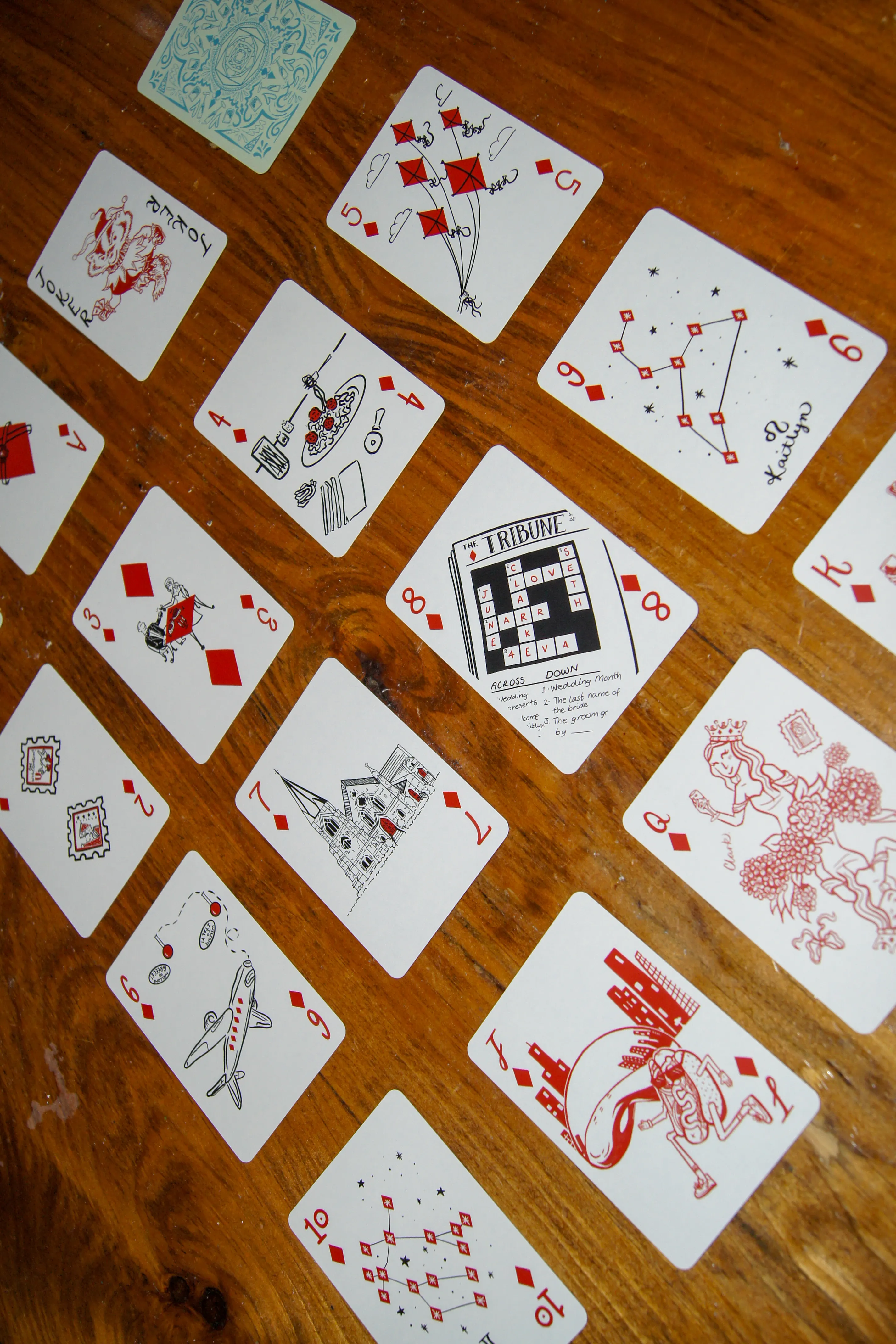 The full suit of diamonds laid out in rows, illustrated in red — kites, a constellation, a newspaper crossword about the wedding, an airplane, and a cathedral.